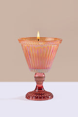  pink candle holder with a lit candle on a beige background